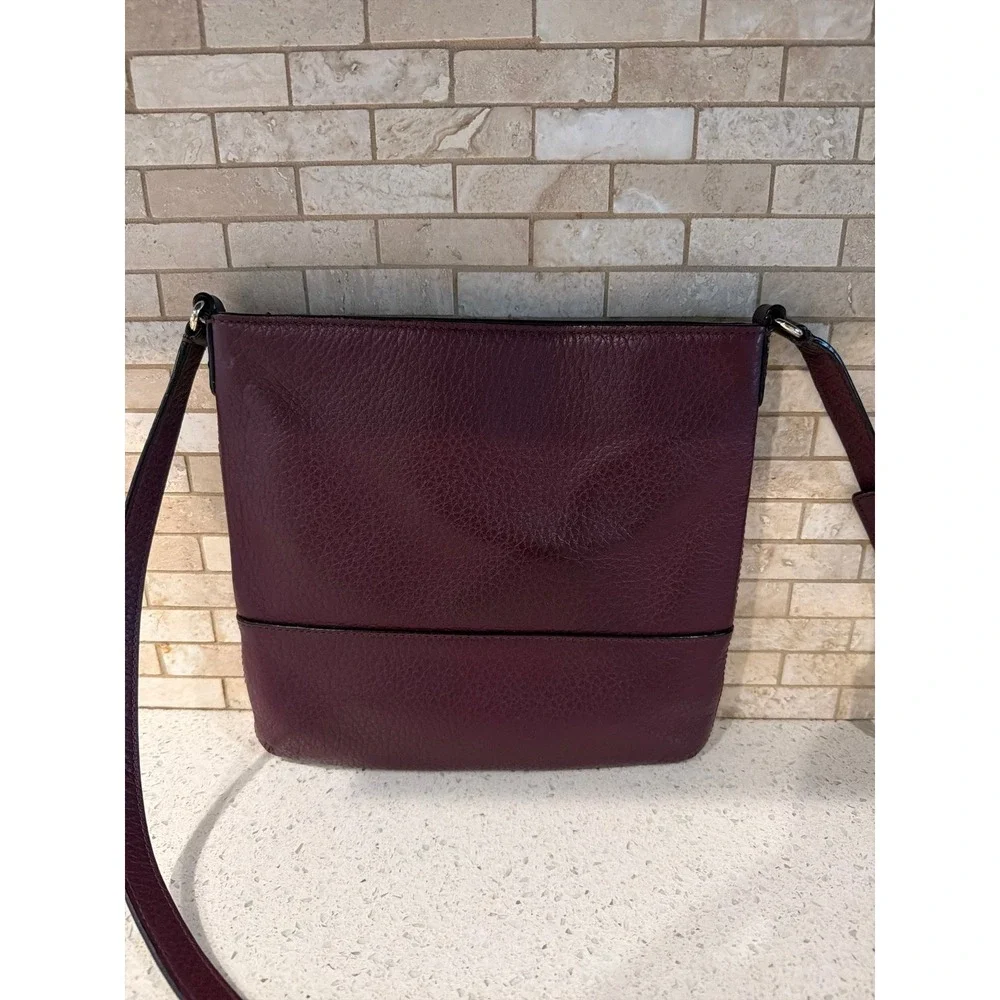 Kate Spade New York pebbled leather crossbody bag in a deep burgundy/wine color.